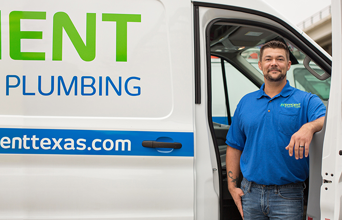 Efficient plumber Dallas Kirk leaning on the door of his work van in Austin, TX.